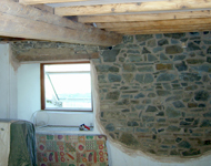 Cleaning wooden beams and exposing interior stone wall.